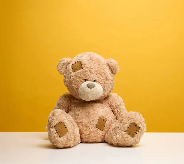 Schattig Bruin Teddybeer Met Patches Zit Een Gele Achtergrond Kinderen — Stockfoto