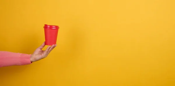 Ręka Trzyma Kartonowy Czerwony Kubek Kawę Żółte Tło Ekologiczne Zastawy — Zdjęcie stockowe
