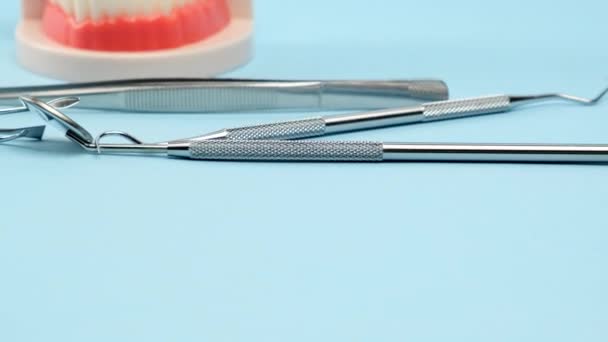 牙龈塑模 带有白牙和各种牙科器械 供医生在口腔内工作时使用 蓝色背景 从右到左相机运动 — 图库视频影像