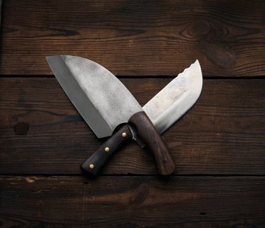Tahtadan yapılmış kahverengi bir masanın ahşap saplı metal keskin mutfak bıçakları.