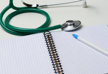 Boş defteri kalem ve steteskopla aç, beyaz masa