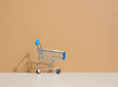 Kahverengi arka planda boş minyatür alışveriş arabası. Mevsimlik satış, fotokopi alanı, online alışveriş