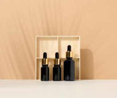 Açık kahverengi arka planda pipeti olan cam kahverengi bir şişe. Cilt makyajı ürünüName