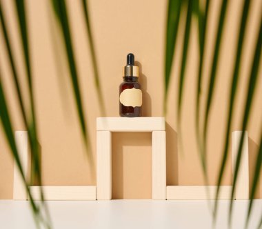 Açık kahverengi arka planda pipetli cam kahverengi şişe ve kağıt boş etiket. Cilt makyajı ürünüName