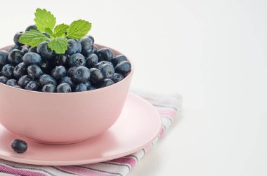 Beyaz bir masada pembe bir seramik tabakta olgun yaban mersini, lezzetli ve kullanışlı bir meyve, kopyalama alanı