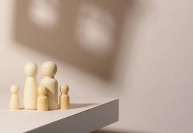 Bir evin arka planında, gölgeli bir ailenin ahşap figürleri. Bej arka plan. Ev hayalleri, ipotek