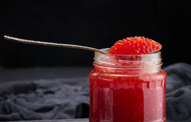 Tahta bir masada cam bir kavanozda taze tahıllı kırmızı havyar.