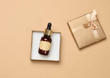 En üstteki kutuda boş etiketli cam şişe. Kozmetik ürünleri ve aroma yağları için konteyner