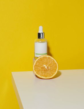 Pipetli beyaz cam bir şişe ve beyaz zemin üzerinde yarım portakal, yeşil arka plan. Citrus özü