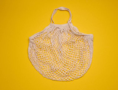 Sarı arka planda boş pamuk torbası. Plastiğin reddi, geri dönüştürülebilir atık