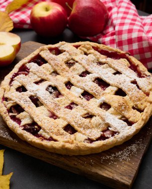 Kahverengi tahta üzerinde geleneksel elmalı turta ve taze kırmızı elmalar.