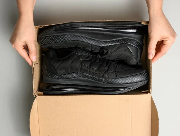 Female Hands Holding Brown Cardboard Box Black Sports Sneakers Gray — Stock Photo, Image