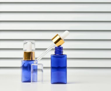 Beyaz arka planda pipeti olan mavi cam bir şişe. Kozmetik sıvı ürünleri, reklamcılık ve tanıtım şablonu