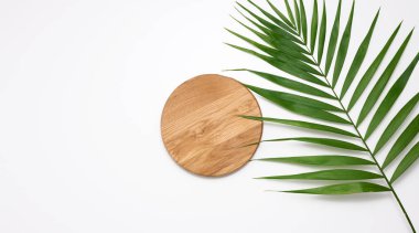 Kahverengi ahşap bir platform kozmetik ürünler, ürünler ve bir palmiye ağacının yeşil yapraklarını sergilemek için. beyaz arkaplan, üst görünüm