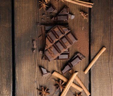 Koyu çikolata parçacıkları, tarçın çubukları ve kahverengi ahşap bir masada yıldız anason.