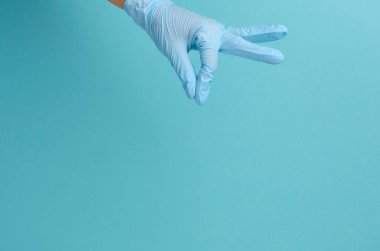 Doktor eli mavi steril lastik eldiven takıyor. Elinde mavi bir nesne var.