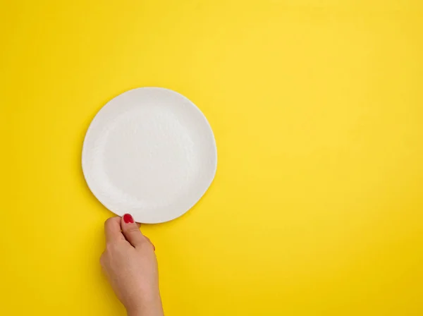 Female Hand Holding White Empty Plate Yellow Background Top View — Stock Photo, Image