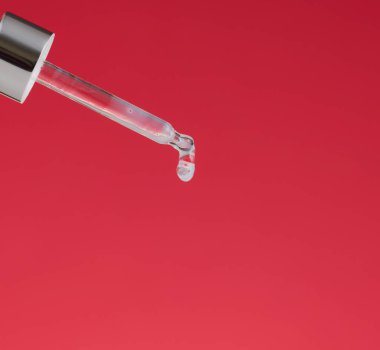 Kırmızı arka planda şeffaf sıvı damlayan cam pipet. Asit, serum.