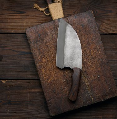 Large kitchen knife on an empty wooden cutting board, top view