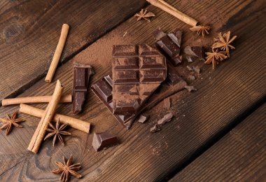 Koyu çikolata parçacıkları, tarçın çubukları ve kahverengi ahşap bir masada yıldız anason.