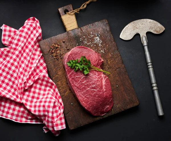 Rauwe Biefstuk Ligt Een Snijplank Specerijen Een Zwarte Tafel Koken — Stockfoto