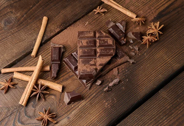 Koyu çikolata parçacıkları, tarçın çubukları ve kahverengi ahşap bir masada yıldız anason.