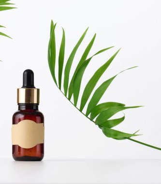 Kahverengi pipetli cam şişe kahverengi arka planda duruyor. Kozmetik, serum ve yağ konteynırı