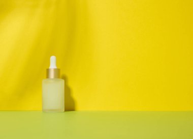 Kozmetik, yağlar, asitler için pipetli beyaz cam şeffaf şişe. Sarı arkaplan