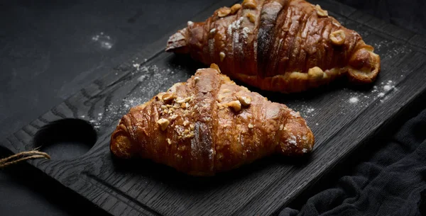 Tahtaya kruvasan konmuş ve üzerine pudra şekeri serpiştirilmiş, siyah masa. Kahvaltı için iştah açıcı hamur işleri.