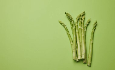 Yeşil kağıttan arka planda bir sürü taze kuşkonmaz. Boşluğu kopyala