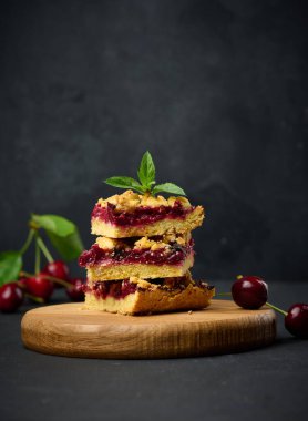 Kare dilimler halinde kiraz parçacıkları siyah bir arkaplanda duruyor, yaz tatlısı.