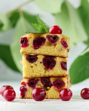 Beyaz ahşap bir tahtanın üzerinde kırmızı kirazlı pişmiş sünger keki.