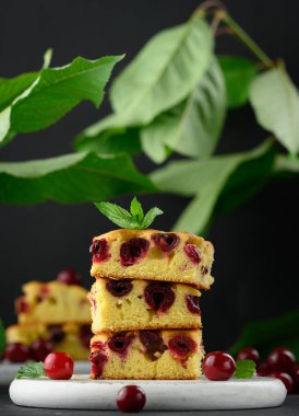 Beyaz ahşap bir tahtanın üzerinde kırmızı kirazlı pişmiş sünger keki.