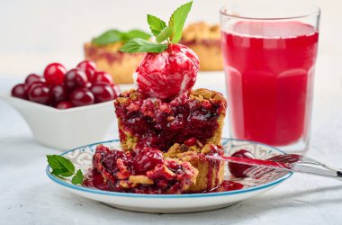 Bir kepçe dondurmayla süslenmiş vişneli turta ve üzerine kiraz sosu serpiştirilmiş.