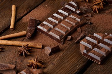 Koyu çikolata parçacıkları, tarçın çubukları ve kahverengi ahşap bir masada yıldız anason.