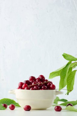 Beyaz bir masada, bir tabakta olgun kırmızı kirazlar.