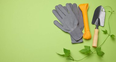 Bahçedeki işleme yatakları için bahçe aletleri ve yeşil arka planda tekstil eldivenleri, üst manzara. Boşluğu kopyala