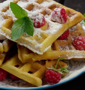 Bir yığın Belçika waffle 'ı olgun kırmızı ahududu serpiştirilmiş pudra şekeri, kahvaltı