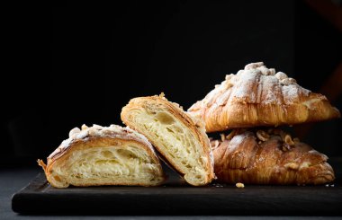 Kurutulmuş kruvasan ve üzerine pudra şekeri serpiştirilmiş, siyah masa. Kahvaltı için iştah açıcı hamur işleri.