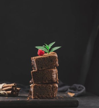 Baked pieces of chocolate brownie pie on black table, delicious dessert