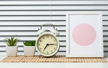 Round alarm clock stands on a white table