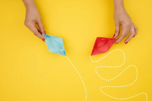 stock image A woman's hand holds paper boats with different trajectories. The concept of optimal problem solving