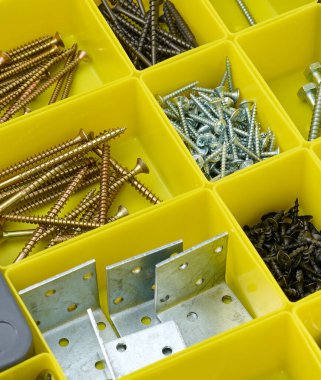 Various metal screws in separate yellow plastic containers. The concept of order and organization of tools