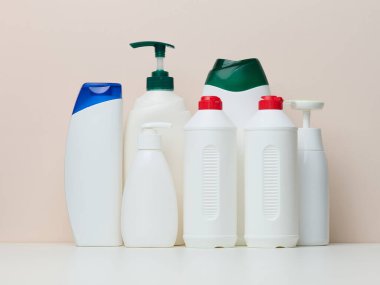 Various white plastic bottles for cosmetics, liquid soap, gel and shampoo on a beige background