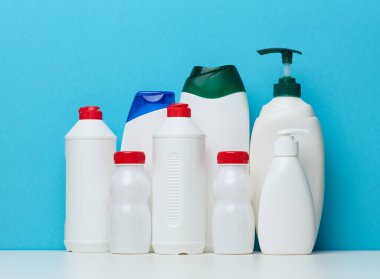 Empty plastic white bottles for cosmetics and other liquid substances on a blue background. Blank for branding gel, shampoo, detergent