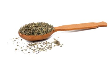 Crushed basil leaves in a brown wooden spoon on a white isolated background