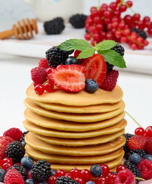 Stack of pancakes with fresh fruits poured with syrup 