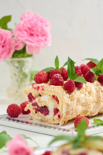 Baked meringue roll with cream and fresh red raspberry, white background