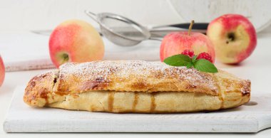 Elma tozu serpiştirilmiş, beyaz tahta üzerine pudra şekeri serpiştirilmiş turta, lezzetli bir tatlı.