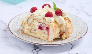 Baked meringue roll with cream and fresh red raspberry, white background	